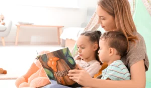 A young woman reading to two little kids.