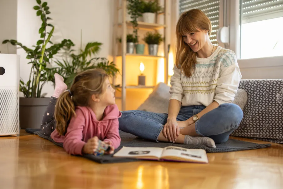 Mother and daughter sitting on floor reading and talking